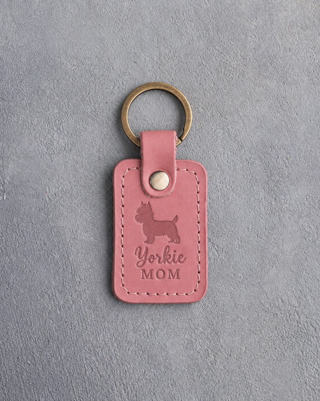 Parisian Blossom pink leather keychain debossed with a Yorkshire Terrier silhouette and the words Yorkie MOM, on gray concrete