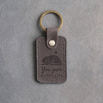 Country gray leather keychain debossed with a curled sleeping dog and one star above the words You gave A GOOD LIFE, on gray concrete
