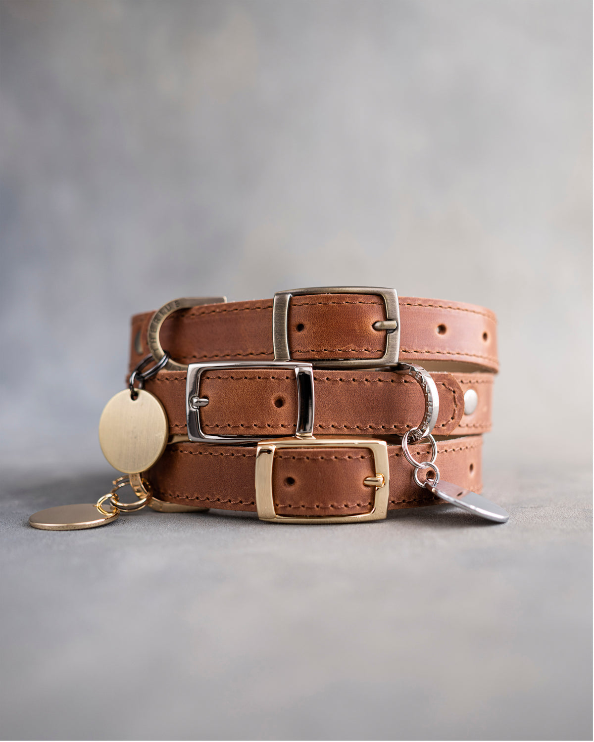 Arizona caramel leather dog collars stacked with pin buckles and a round engraved ID tag