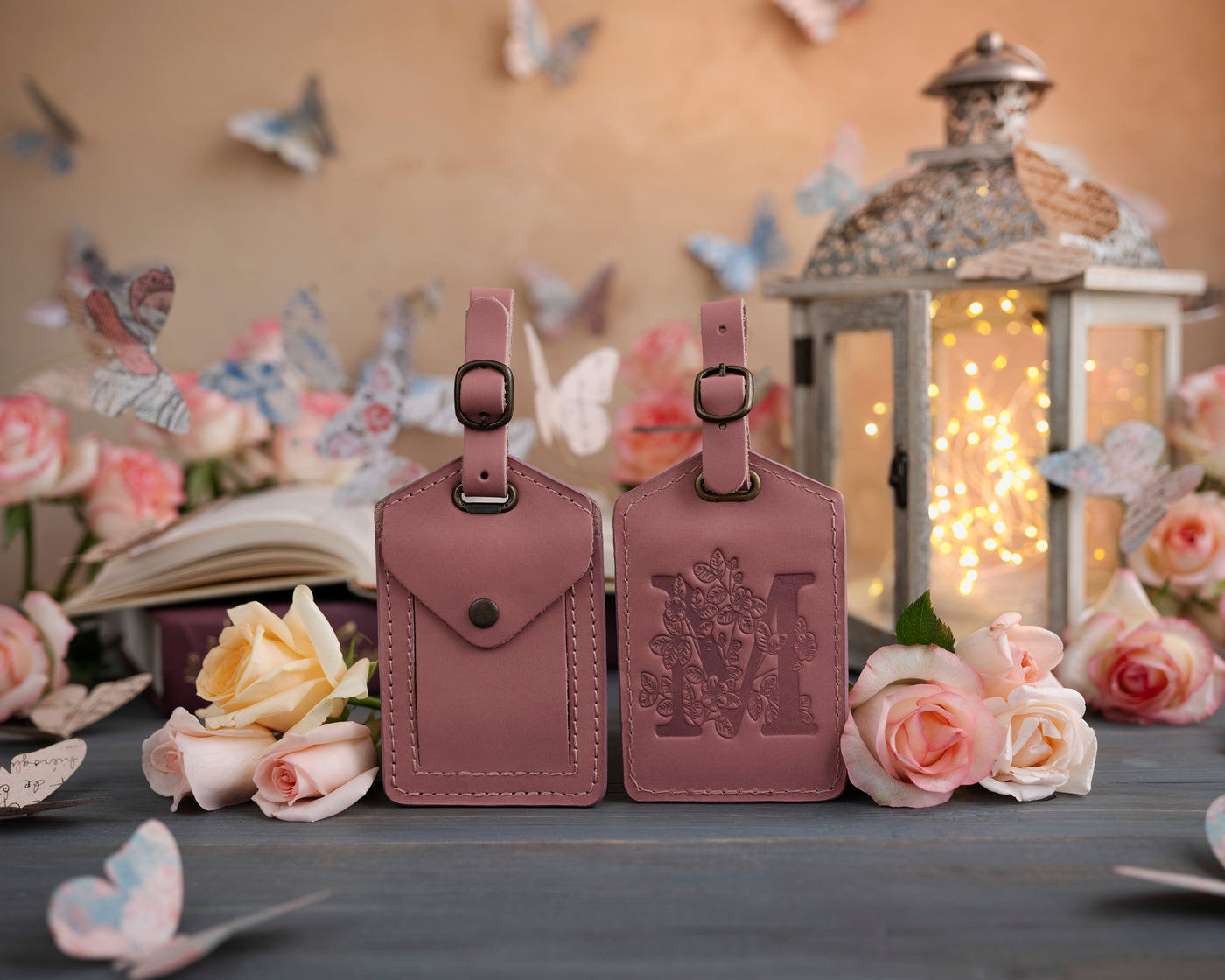 Parisian blossom leather luggage tag showing the floral initial front and address-card back, staged with roses