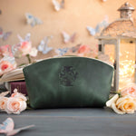 Initial leather makeup bag in forest green with a floral monogram deboss, roses and a glowing lantern behind