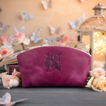 Fuchsia leather makeup bag stamped with a floral initial N, surrounded by blush roses