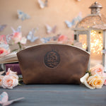 Sicilian brown leather makeup bag with a rounded floral monogram deboss among roses